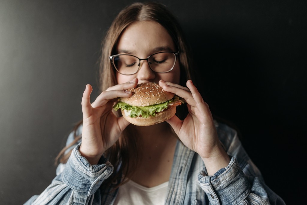 A woman binge-eating a burger.