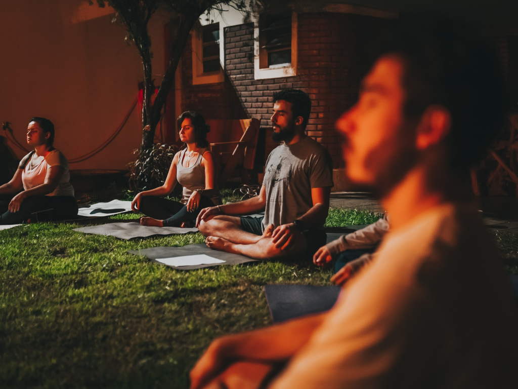 A bunch of people performing group meditation in a meditation centre