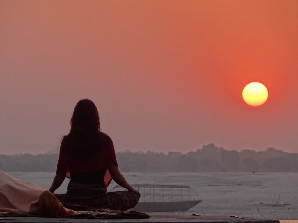 An image of woman performing morning meditation during sunrise