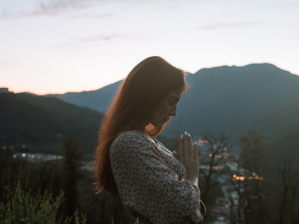 An image of a woman performing prayer meditation during sunrise