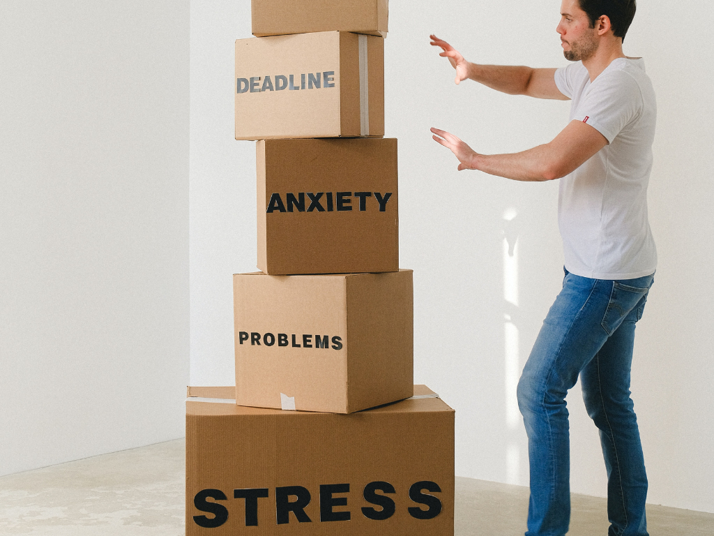 An image of a man near carton boxes with many different words about stress.